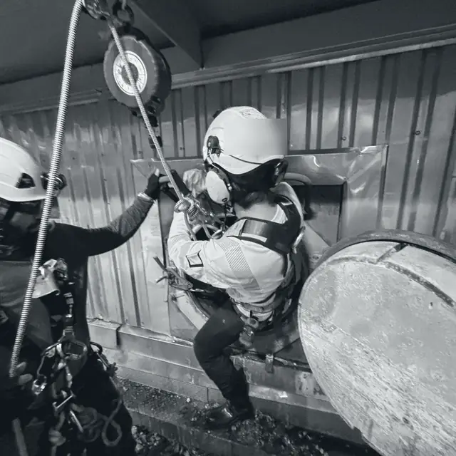 Maniobra de rescate con cuerdas sobre un equipo industrial.